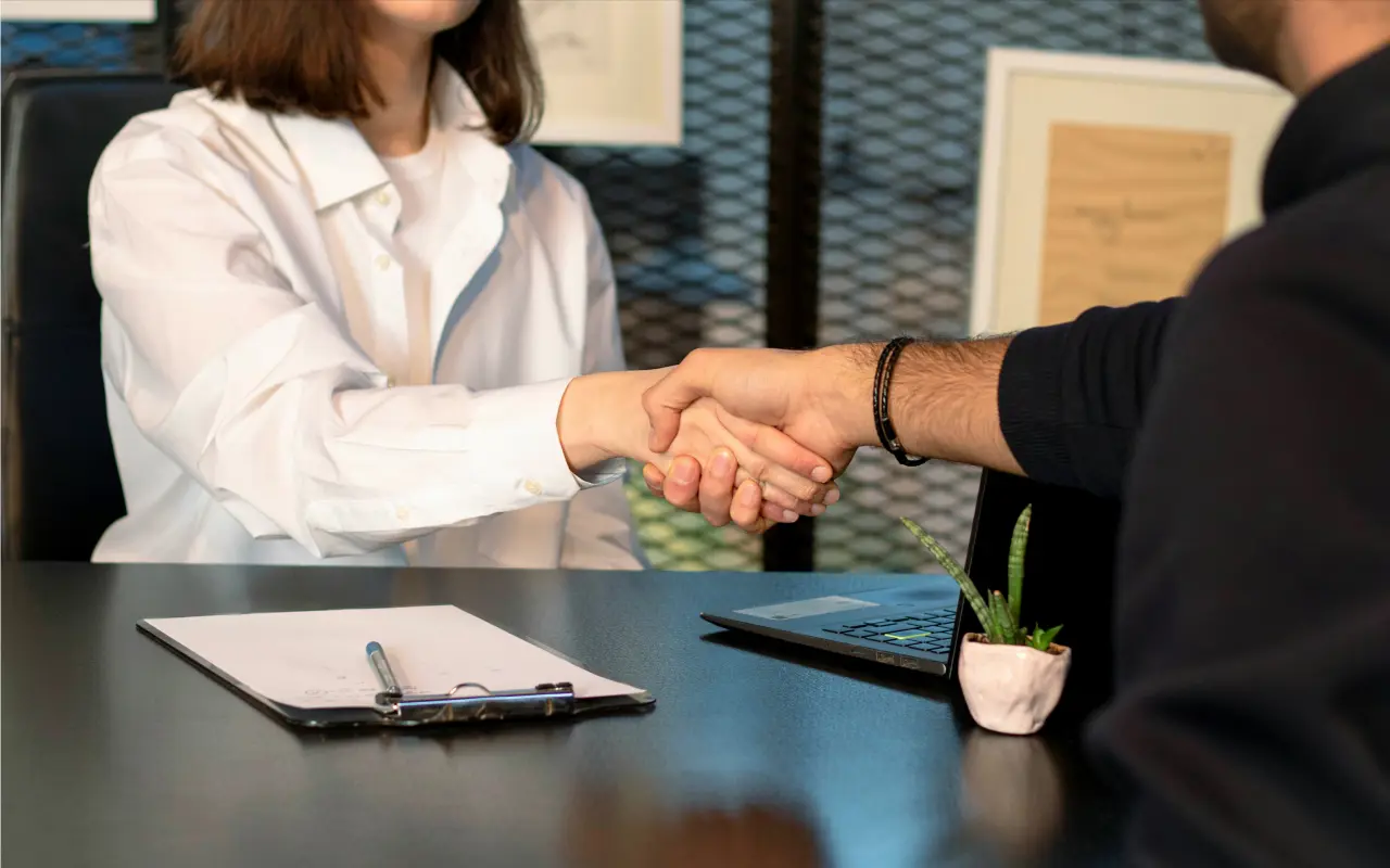 Uomo e donna che si stringono la mano in una stanza di ufficio